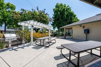 a large patio with picnic tables and a grill